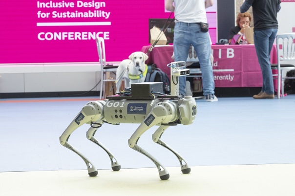 A canine guide dog stares down its robot equivalent at the 2023 Conference